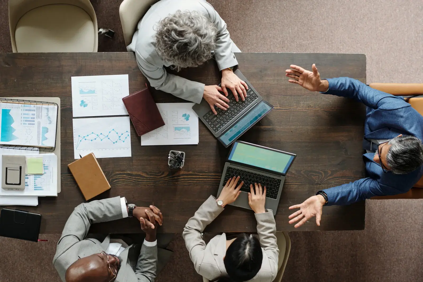 Overhead view of a team planning a project around a table with laptops